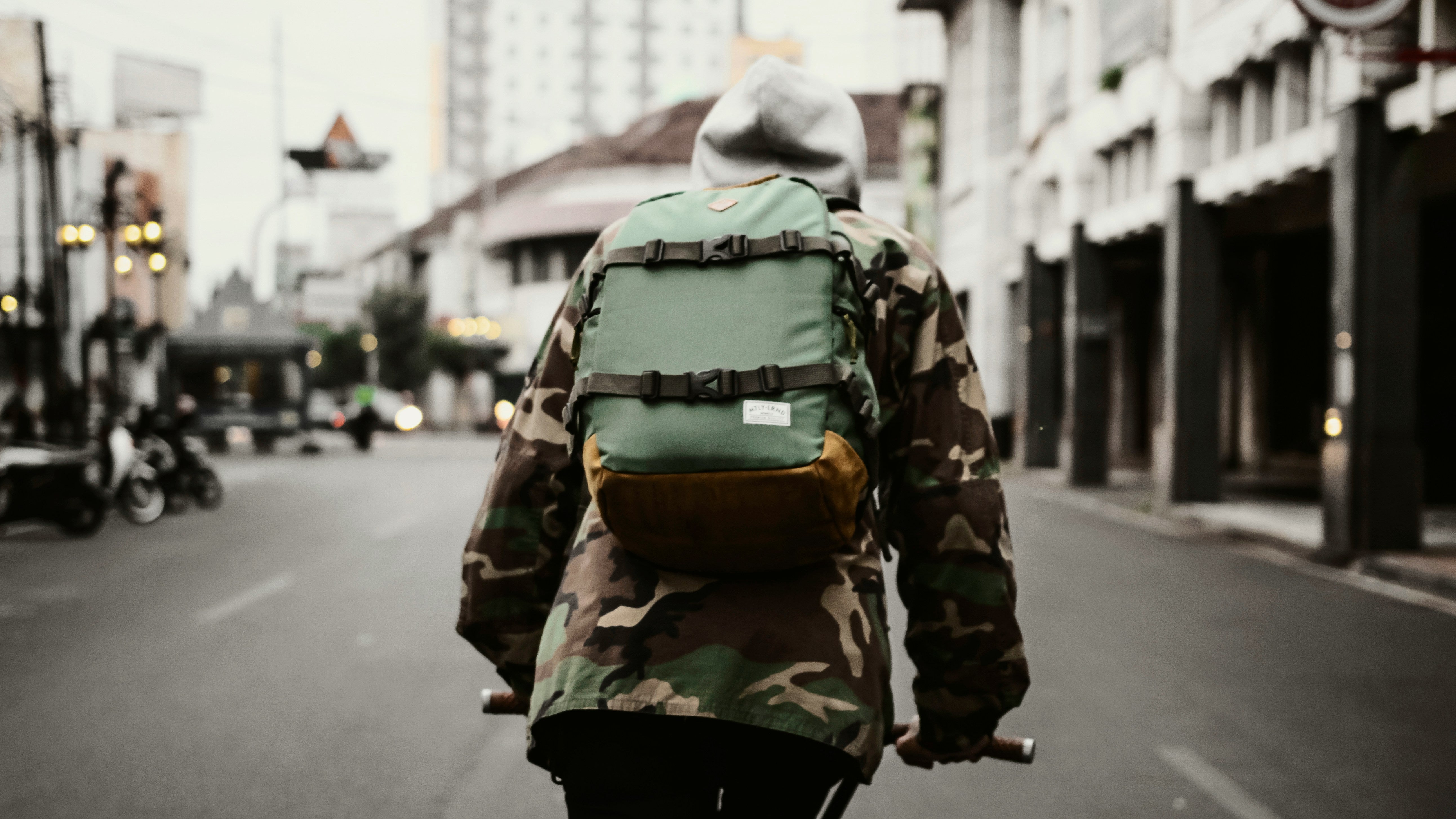 Backpack; a man wearing a backpack riding on a bike - rear view